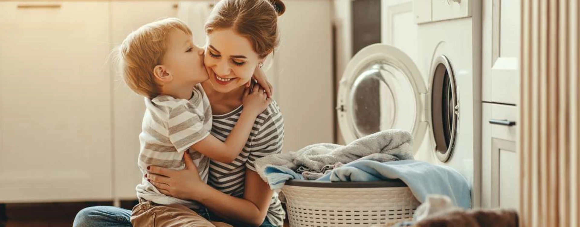 kid kissing mother next to the washing machine